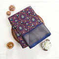 Art silk saree with floral vine jaal pattern and silver zari striped border in dark blue folded top view display