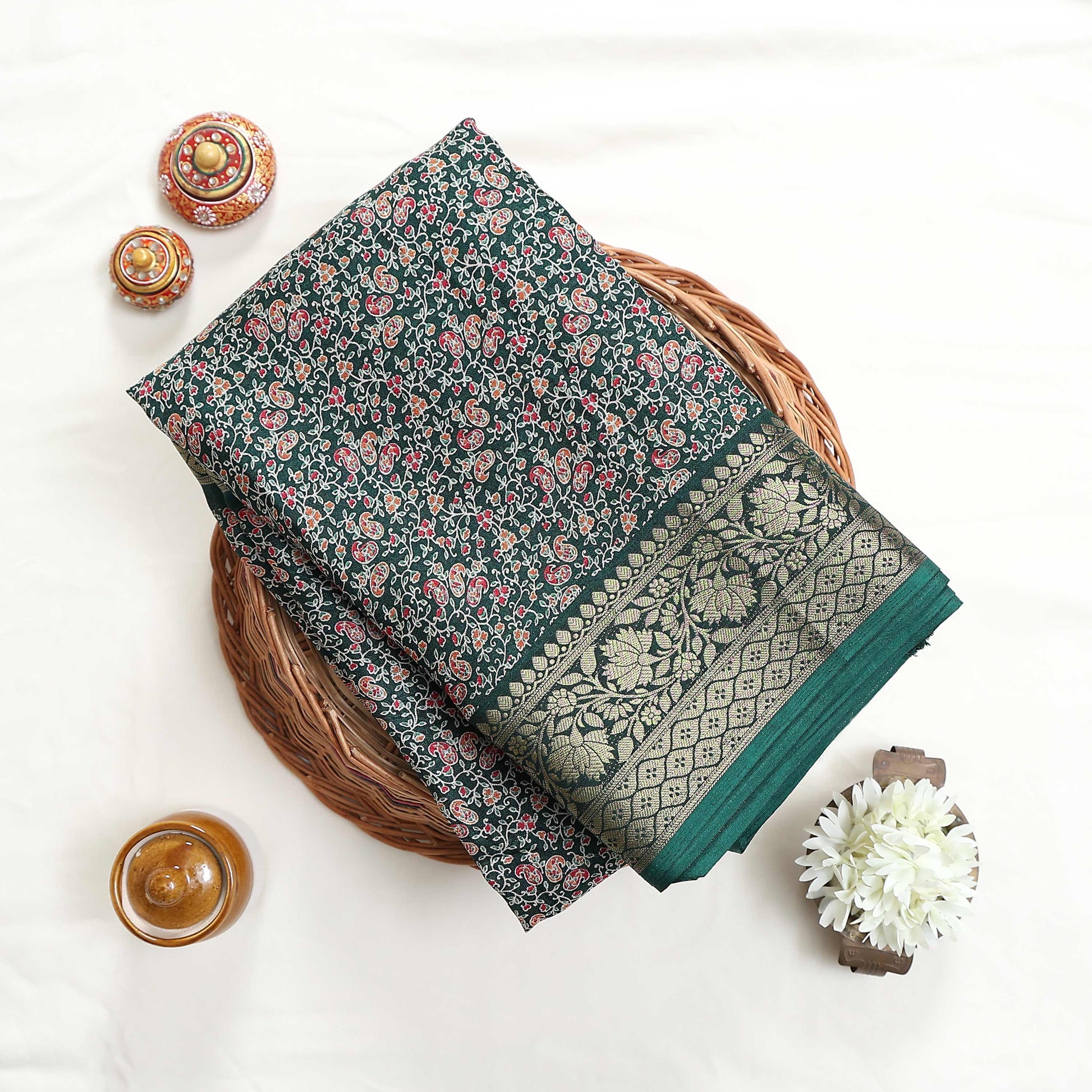 Green art silk saree with floral paisley jaal pattern and broad zari border folded flat lay view