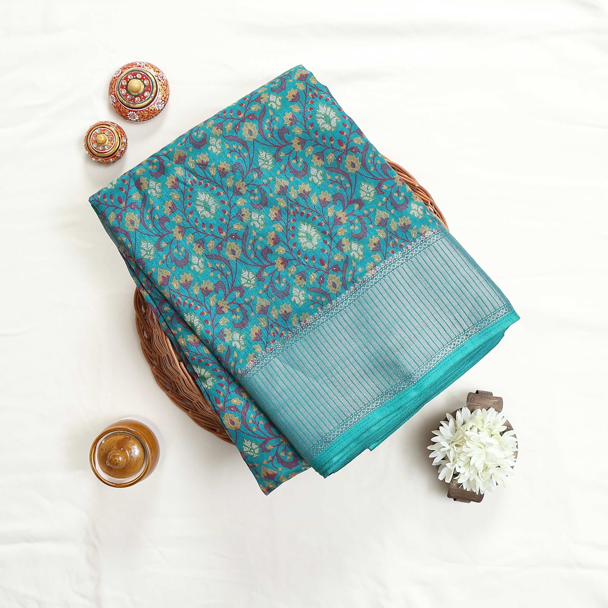 Art silk saree with floral vine jaal pattern and silver zari striped border in green folded top view display
