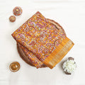 Art silk saree with intricate paisley floral print in yellow and gold woven border folded flat lay view in a wicker basket