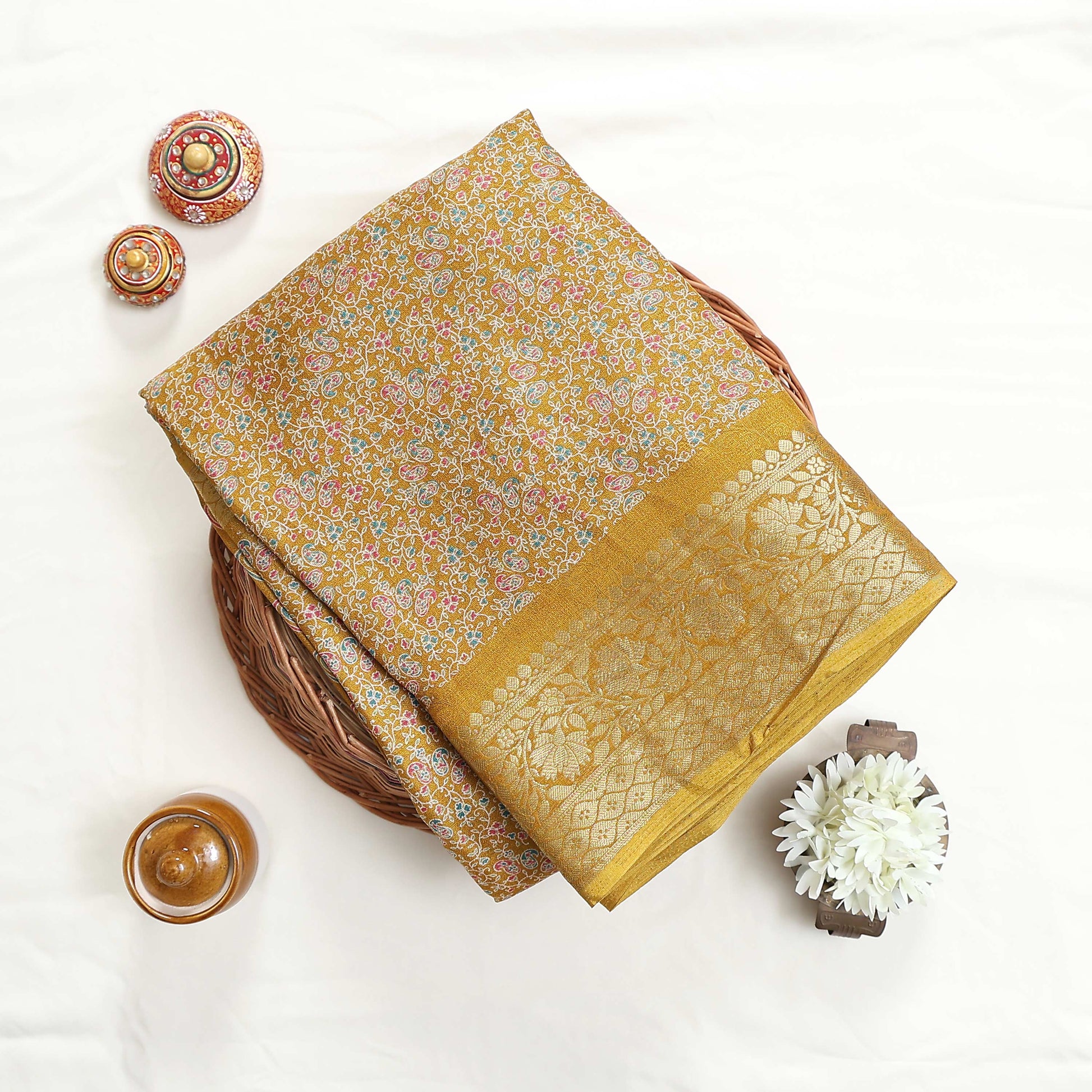 Yellow art silk saree with floral paisley jaal pattern and broad zari border folded flat lay view