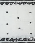 Black floral embroidered cotton saree with sheer white fabric and intricate black vine border front view.