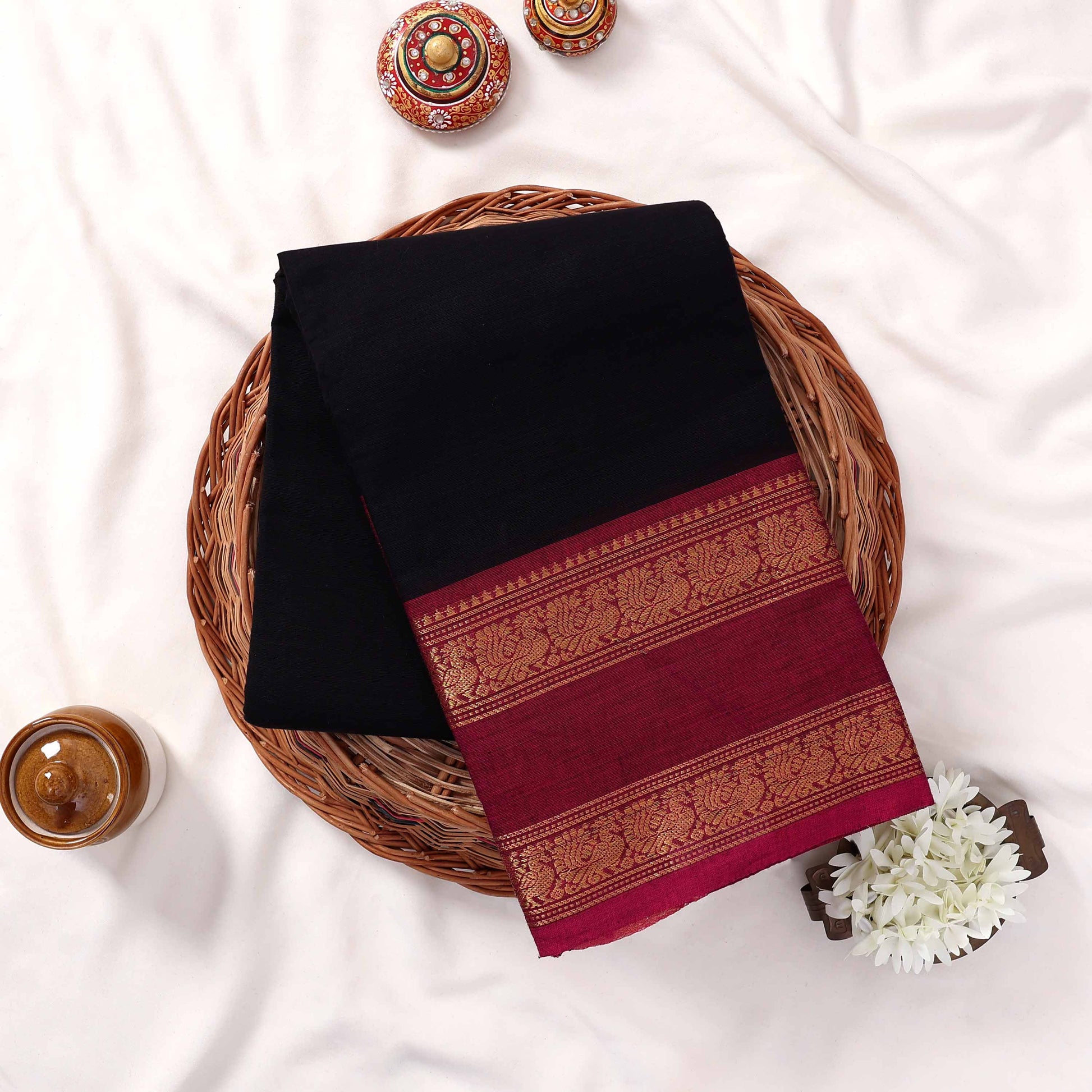 Kanchi Cotton Saree With Black Body And Magenta Gold Zari Border Neatly Folded In Basket Top View Styling
