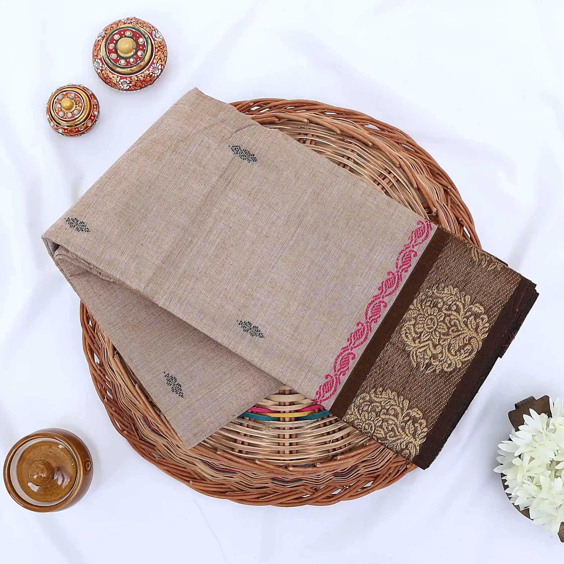 Chettinad cotton saree with floral zari border in beige and brown folded flat lay showcasing woven motifs and border detail.