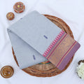Chettinad cotton saree with temple zari border and grey body featuring woven buttas folded top view.