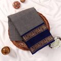 Kanchi Cotton Saree With Elegant Grey Body And Royal Blue Zari Border Folded In Basket Top View Display Traditional Wear
