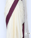 An off-white/cream saree featuring a deep purple border with a white geometric pattern - head view