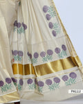 A cream-colored kerala saree with a metallic gold border and purple floral embroidery near the hem pallu view