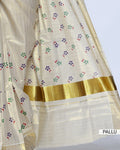 A cream-colored kerala saree with gold zari stripes and small colorful floral motifs, pallu view