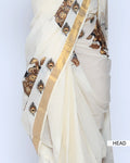 An off-white saree with gold zari borders and brown printed motifs head view