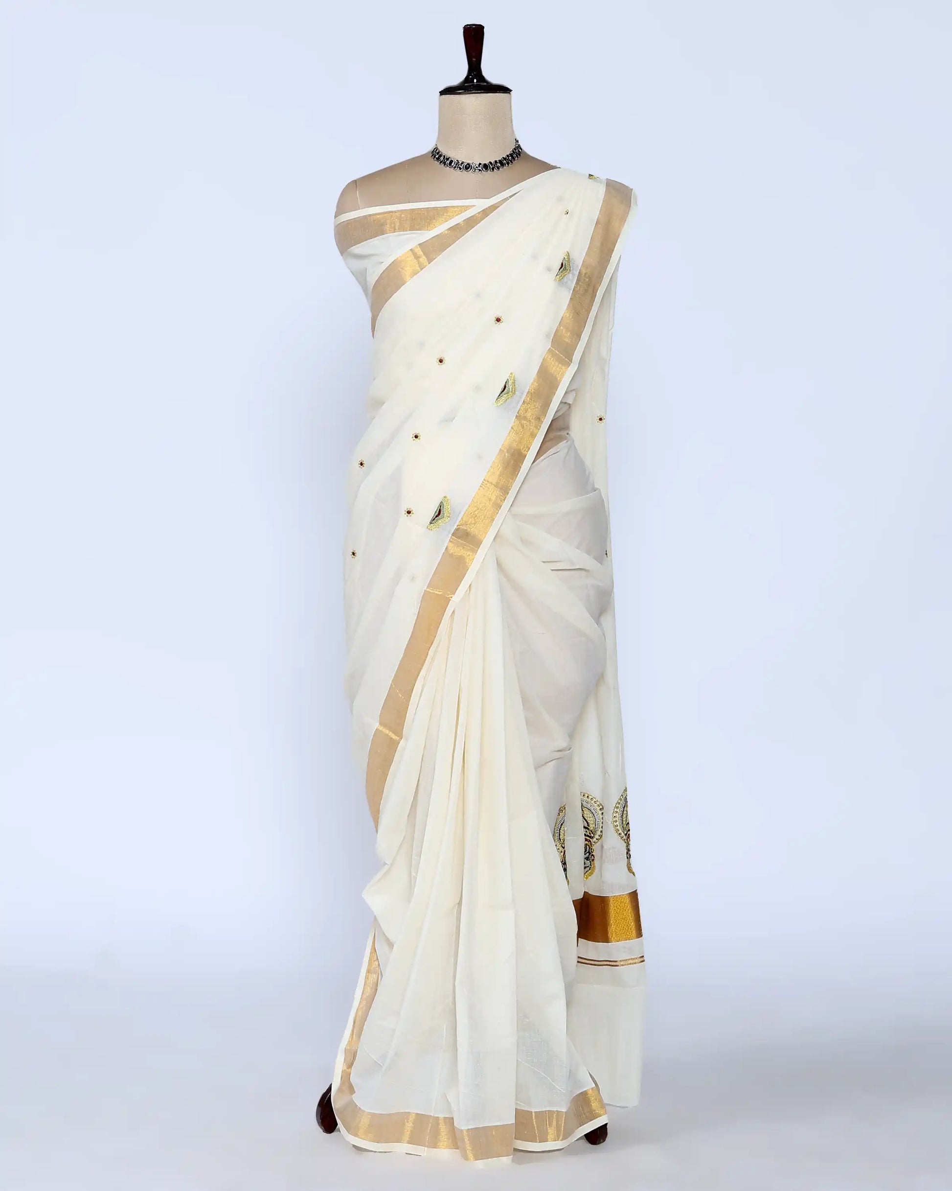 An off-white cotton saree with gold zari borders and small gold dots full view