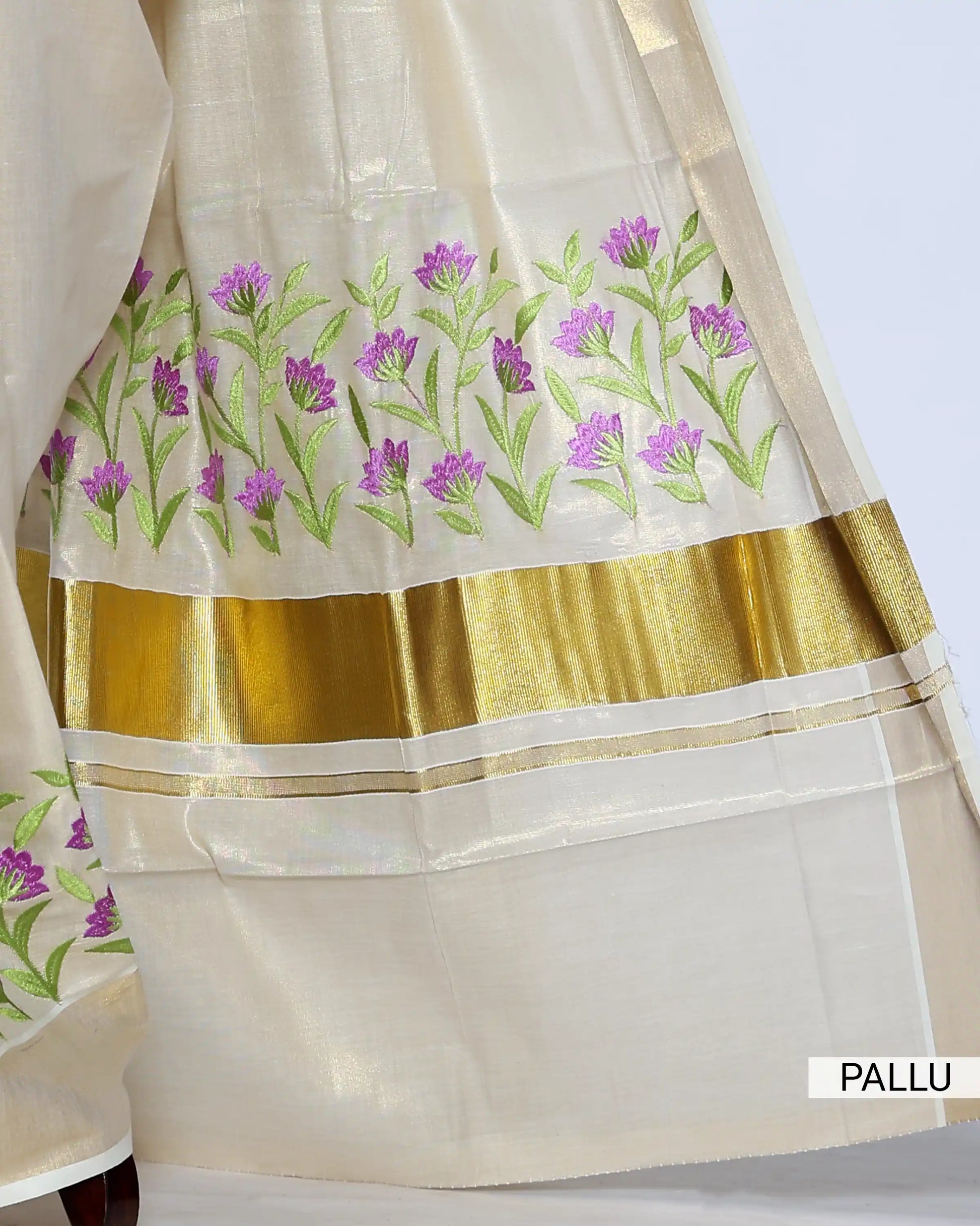 A cream-colored Kerala saree with purple and green floral embroidery pallu view