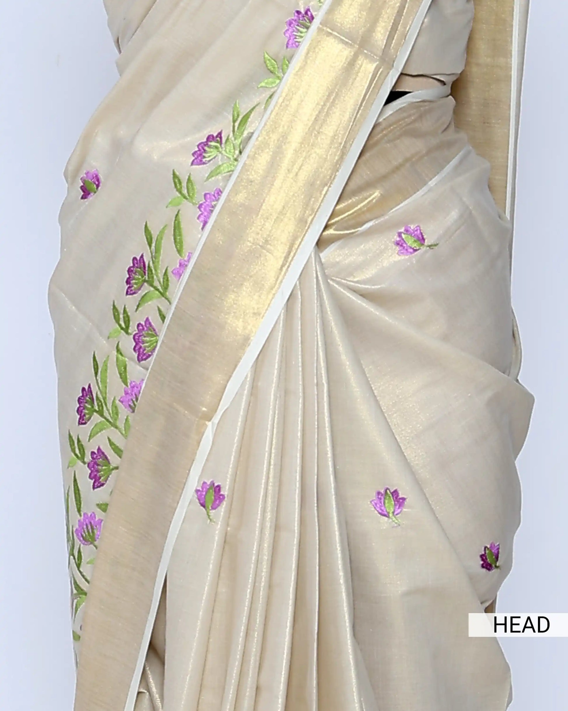 A cream-colored Kerala saree with purple and green floral embroidery Head view
