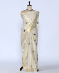 A cream-colored silk saree with small purple and gold floral motifs - full view