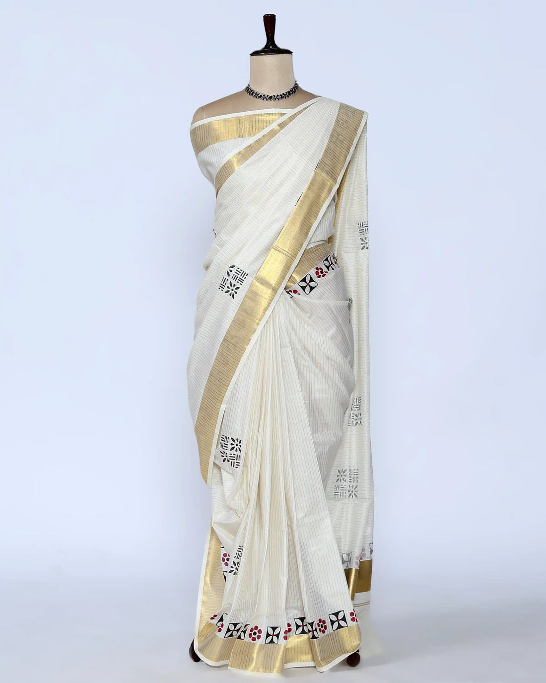 An off-white cotton saree with a wide gold border and small black and red floral motifs - full view