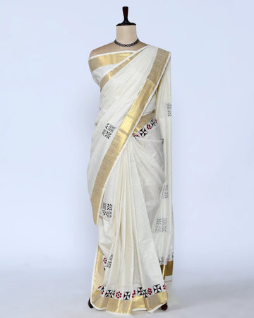 An off-white cotton saree with a wide gold border and small black and red floral motifs - full view