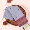Kanchi Cotton Saree With Light Blue Body And Pink Gold Woven Border Flat Lay Top View On Woven Basket Display
