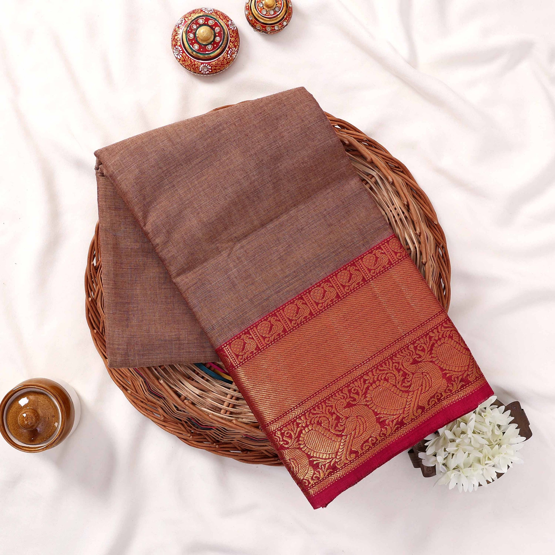 Folded Kanchi Cotton Saree Showcasing Detailed Gold Zari Motifs And Magenta Border Overhead Display View

