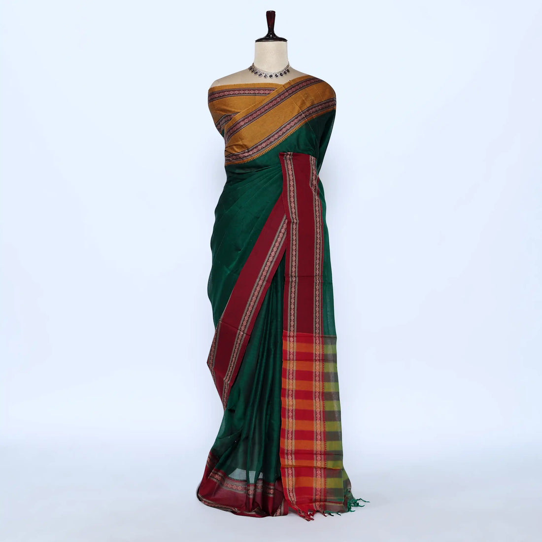 A dark green silk saree with a gold and red patterned blouse and a red border