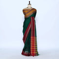 A dark green silk saree with a gold and red patterned blouse and a red border