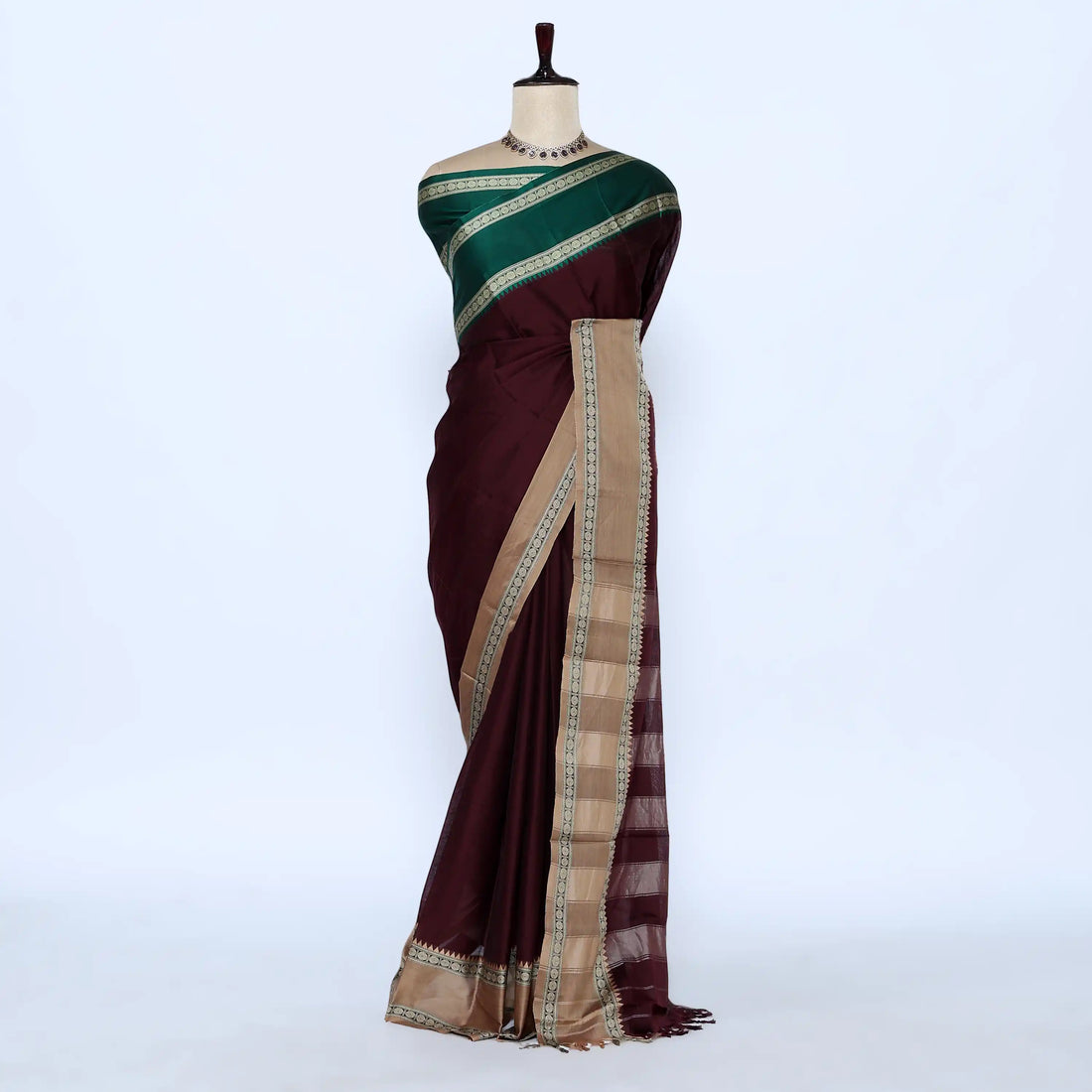 A dark maroon and green saree  features a deep maroon body, a dark green blouse, and a beige and border.