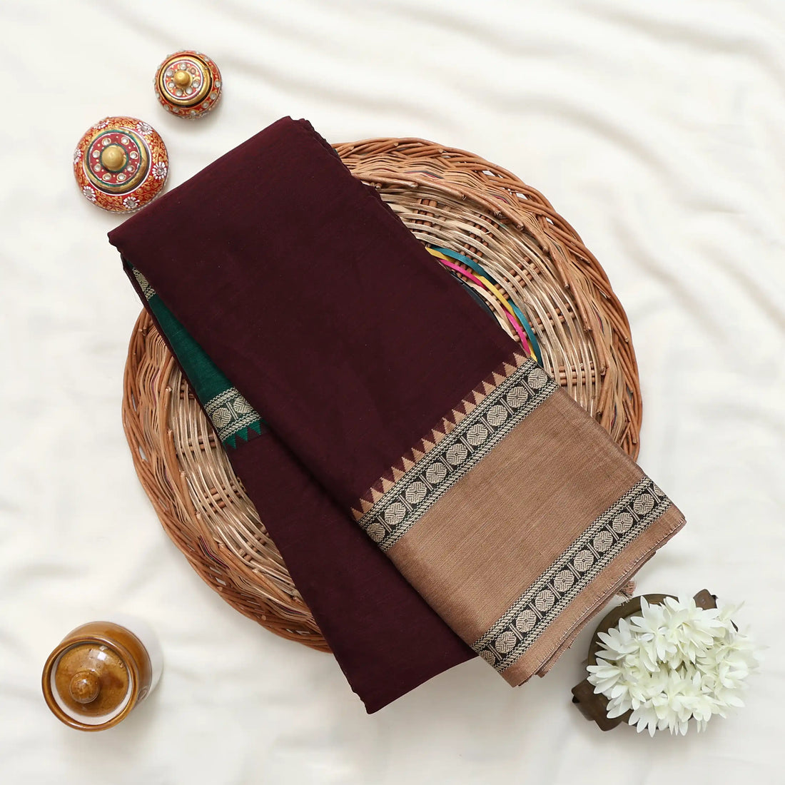A dark maroon and green saree  features a deep maroon body, a dark green blouse, and a beige and border.