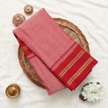 A folded red and pink saree with gold zari borders