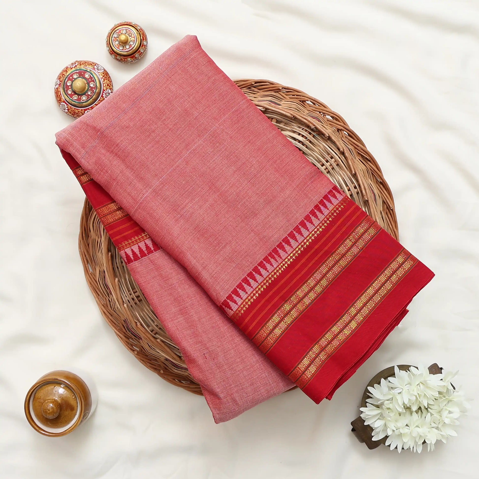 A folded red and pink saree with gold zari borders