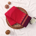 Kanchi Cotton Saree With Contrasting Maroon Zari Border In Bright Pink Folded Flat Lay View On Woven Basket
