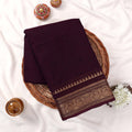 Kanchi Cotton Saree With Intricate Gold Zari Border In Deep Purple Neatly Folded On Wicker Basket Top View
