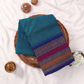 Kanchi Cotton Saree With Teal Blue Body And Ornate Multicolor Woven Border Folded Display On Wicker Tray Top View
