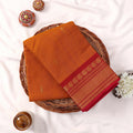 Kanchi Cotton Saree With Gold Zari Border In Yellow And Magenta Neatly Folded On A Wicker Tray Top View
