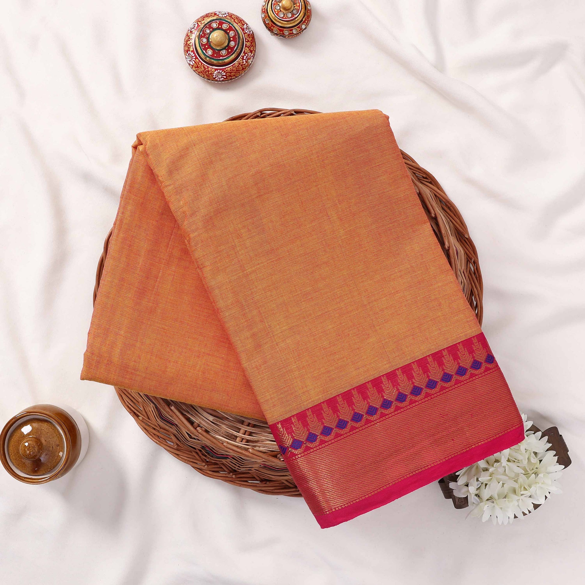 Kanchi Cotton Saree With Zari Weave And Pink Border In Yellow Neatly Folded Flat Lay View With Decorative Accents
