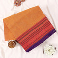 Chettinad cotton saree with a yellow body red zari woven border and purple edge folded flat top view.
