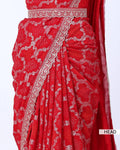 A close-up of a red saree with intricate silver floral prints and a silver border