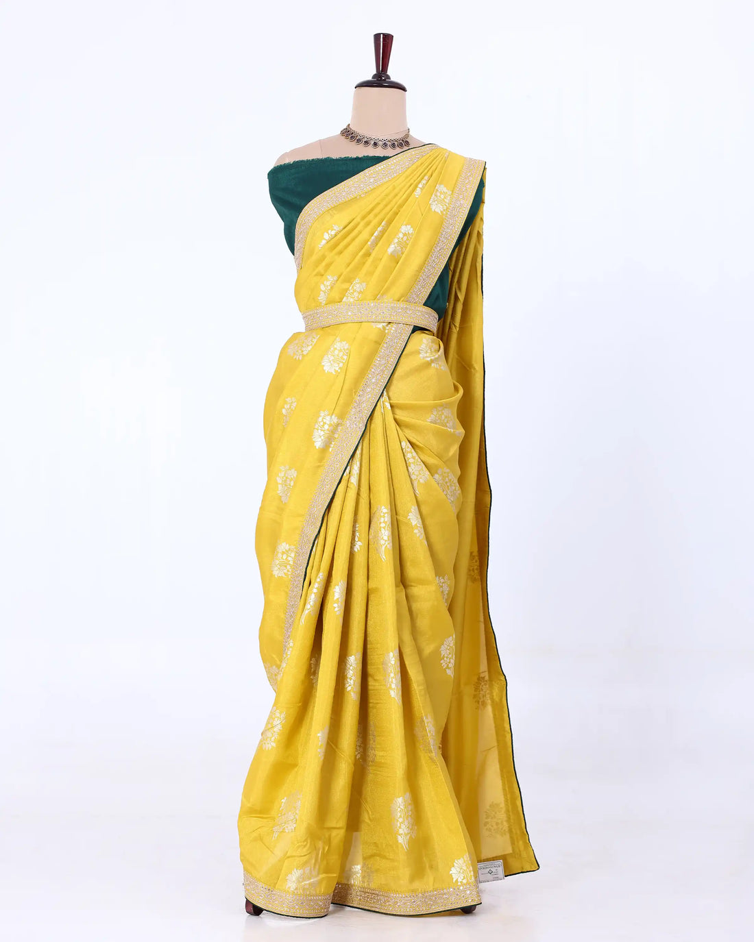 A yellow Fancy saree with silver zari floral motifs, paired with a dark green blouse