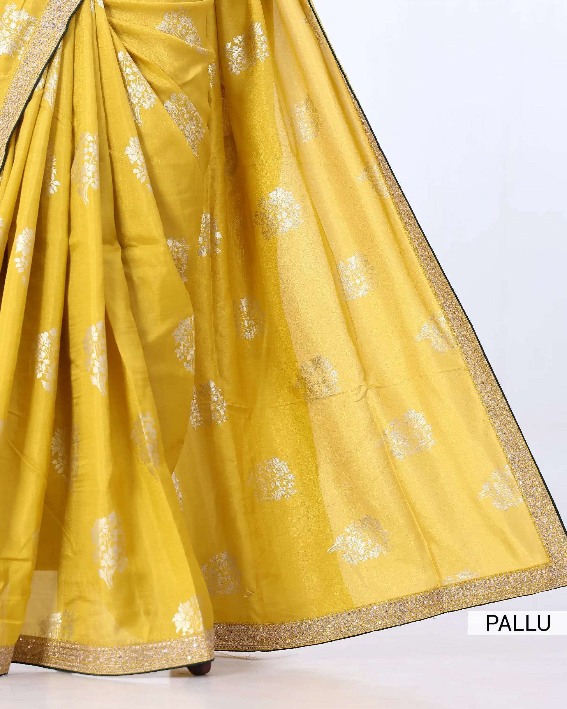 A close-up of a yellow saree with metallic silver floral motifs and a gold border