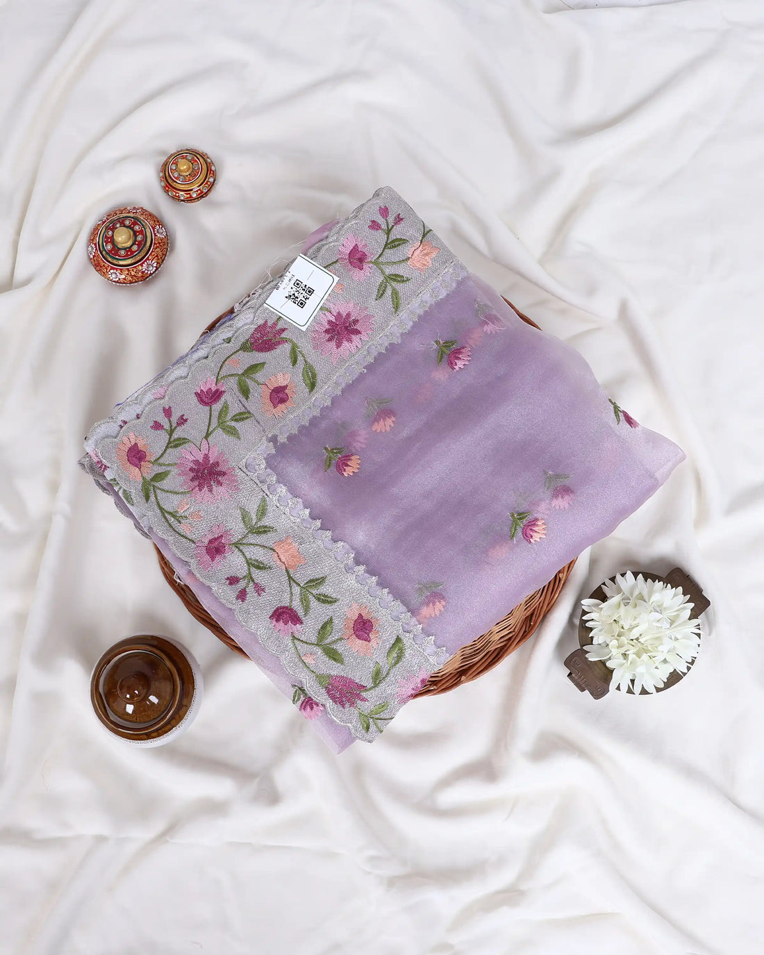 A light purple/lavender saree with floral embroidery and a matching border