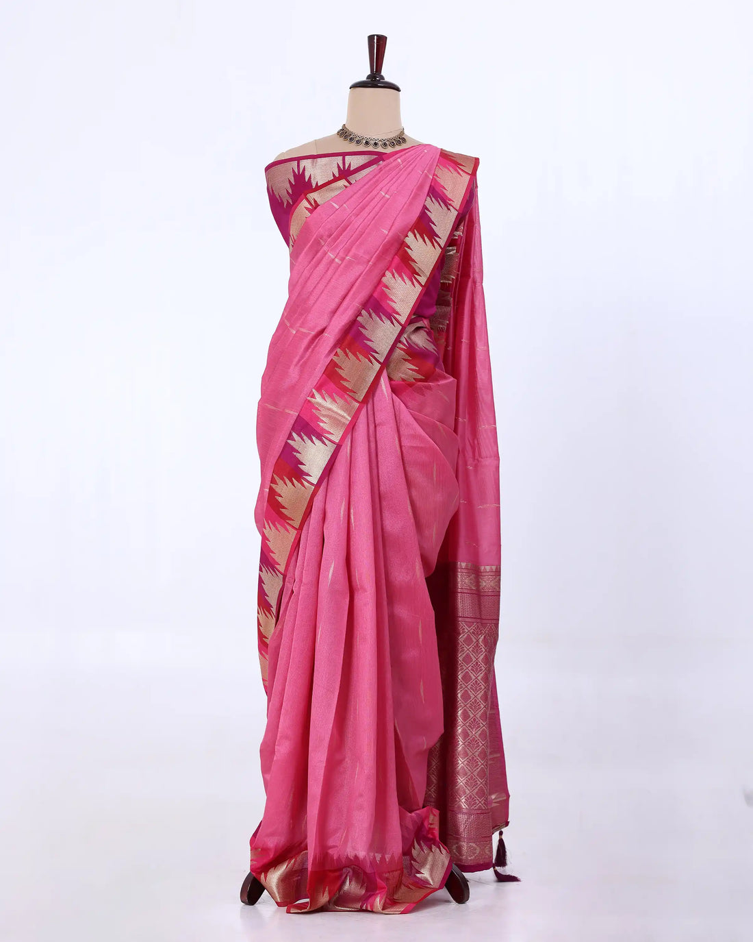 A pink silk saree with a metallic gold and beige geometric border