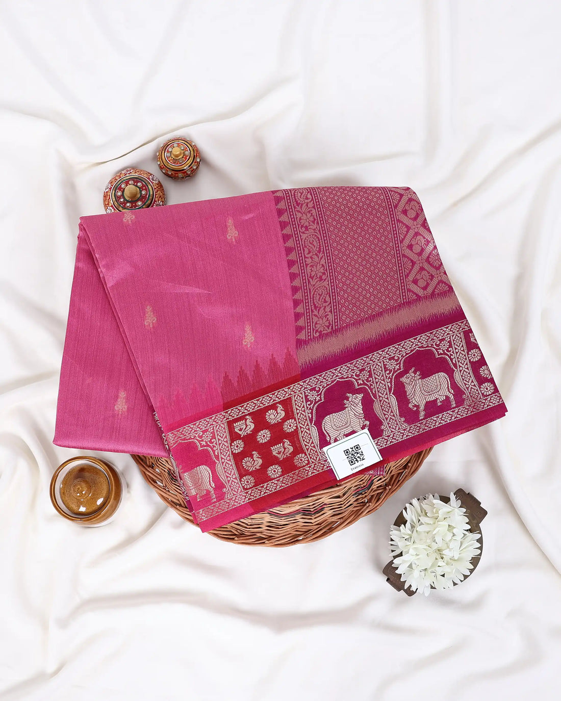 A pink silk saree with a detailed red and gold border