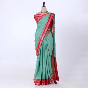 A mint green and red saree with a mint green body with a red border and a red pallu, accented with gold zari metallic patterns.