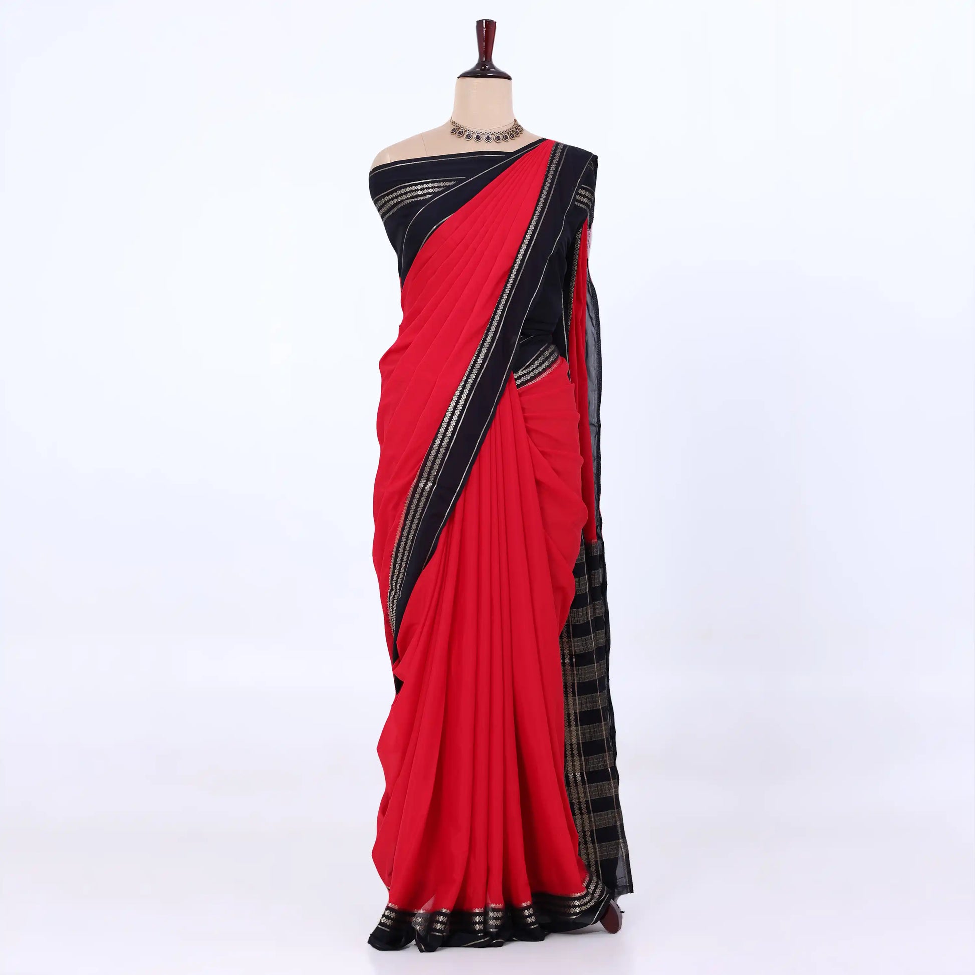 A red and black saree featuring a black blouse with gold stripes and a matching black patterned pallu with gold detailing