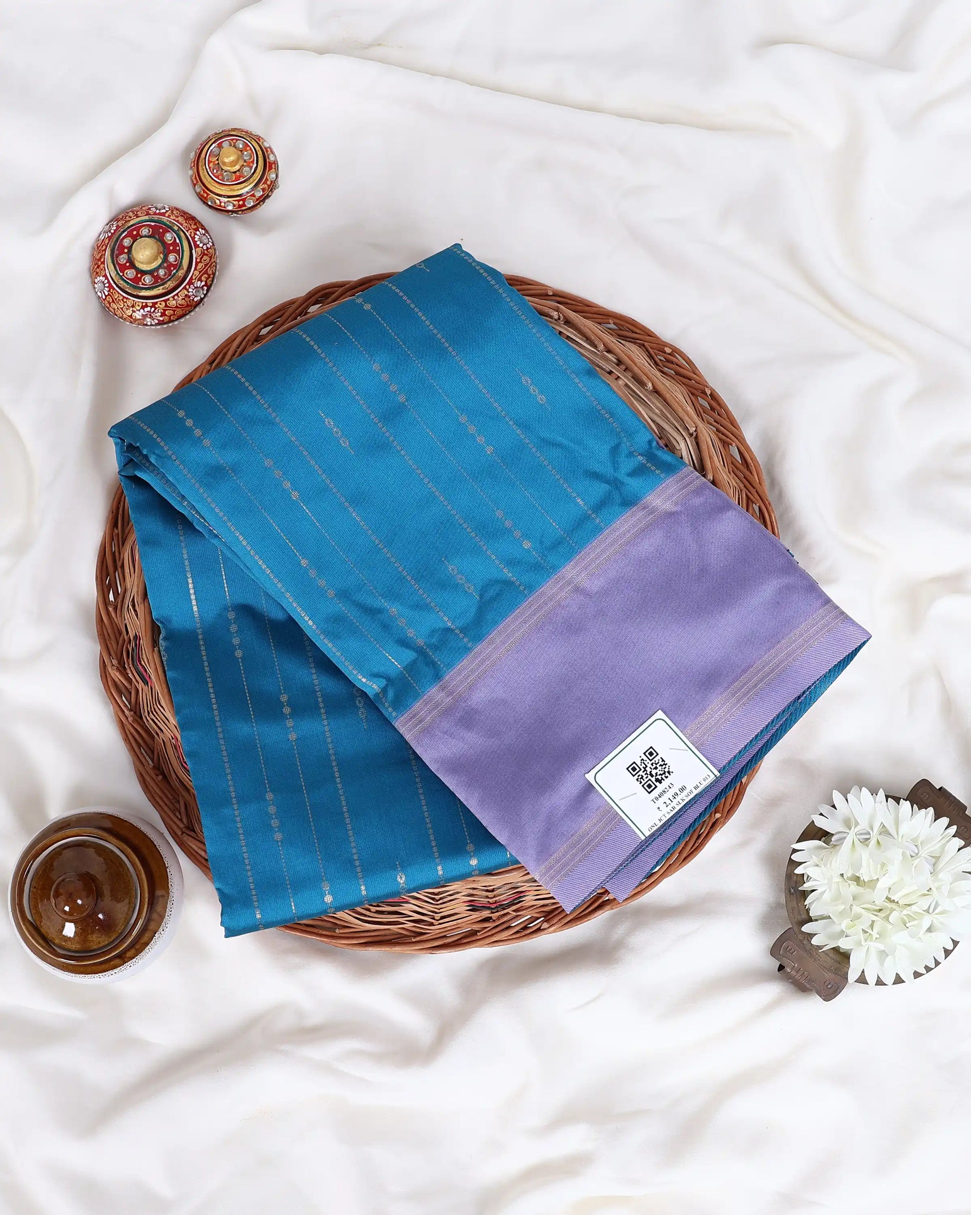 A folded blue and purple saree with gold zari stripes