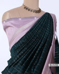 A dark green pleated silk saree with thin silver stripes, paired with a light purple/lavender blouse