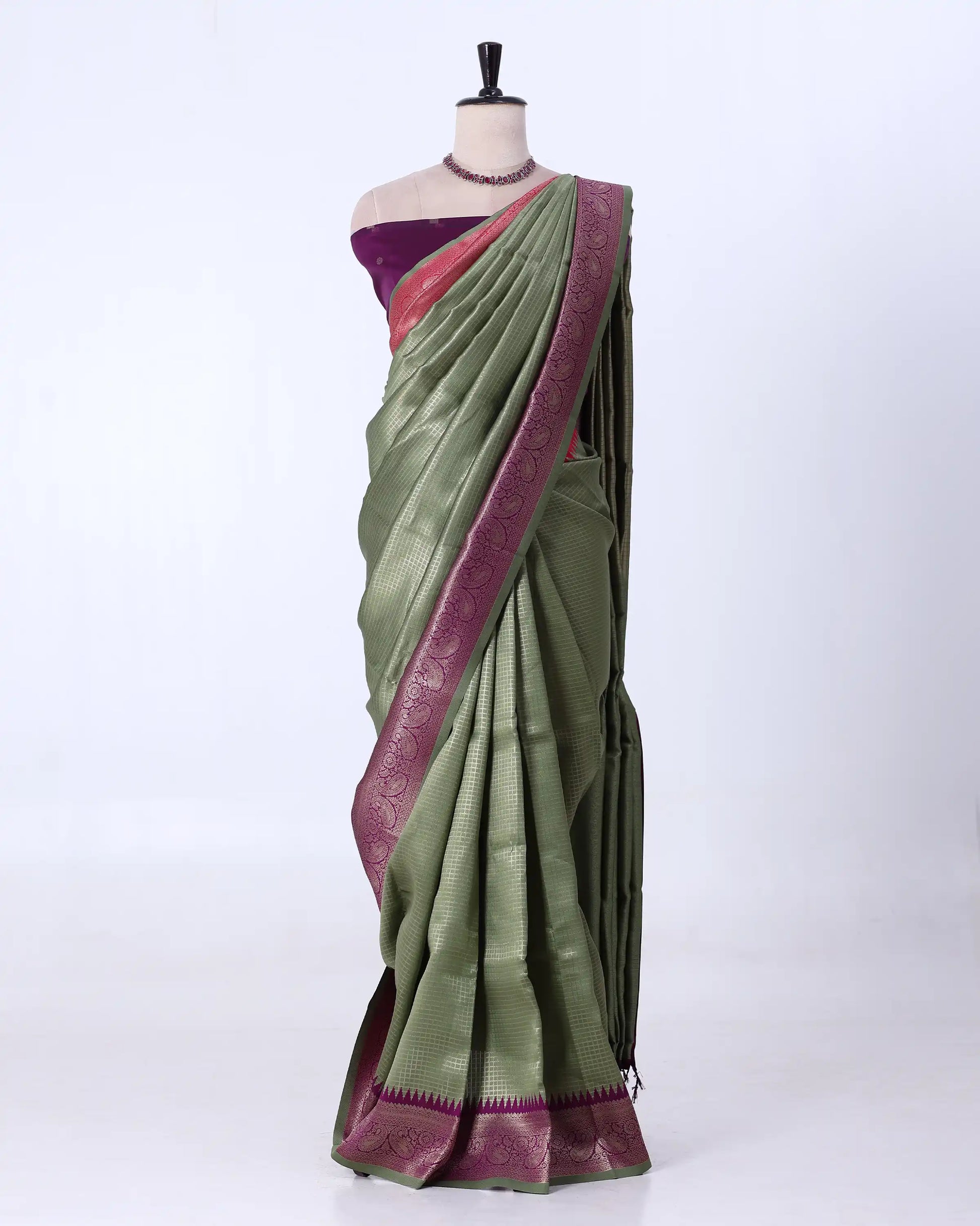 An olive green silk saree with a deep purple border and a matching purple blouse