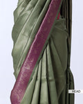 An olive green saree with a wide magenta-purple border featuring metallic paisley and floral motifs