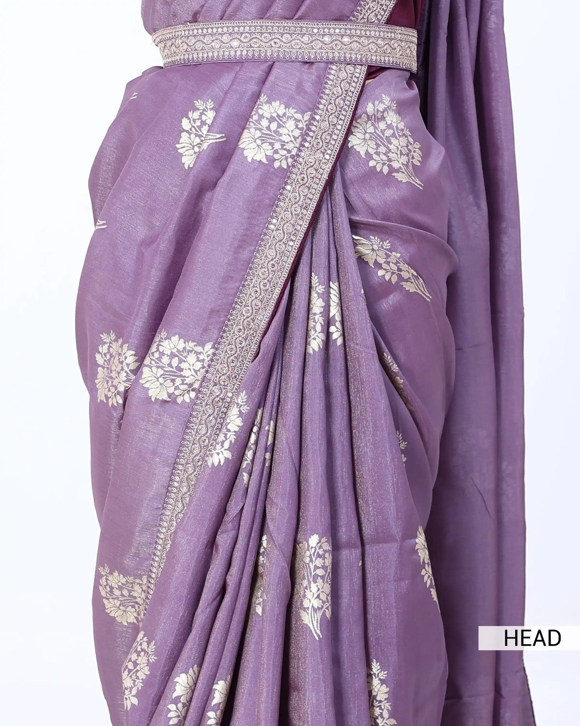 A close-up of a draped purple saree with white floral motifs and a decorative border