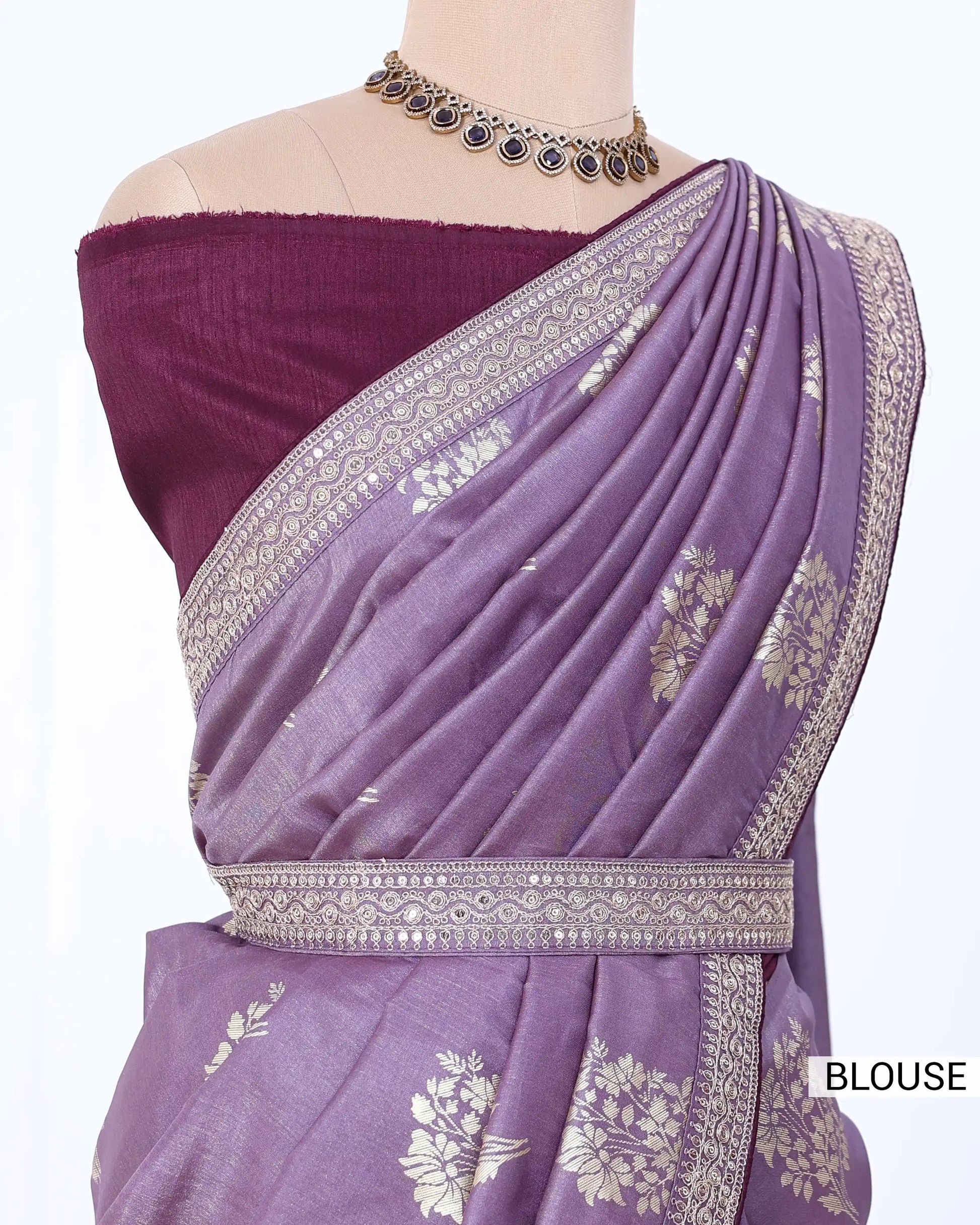 A lavender purple saree with silver floral zari embroidery, paired with a deep purple off-the-shoulder blouse. 