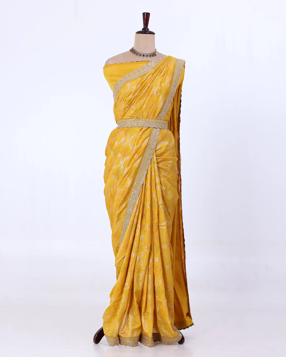 A yellow saree with gold zari embroidery and a matching waist belt
