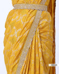 A close-up of a yellow saree with silver floral embroidery and a wide embellished border